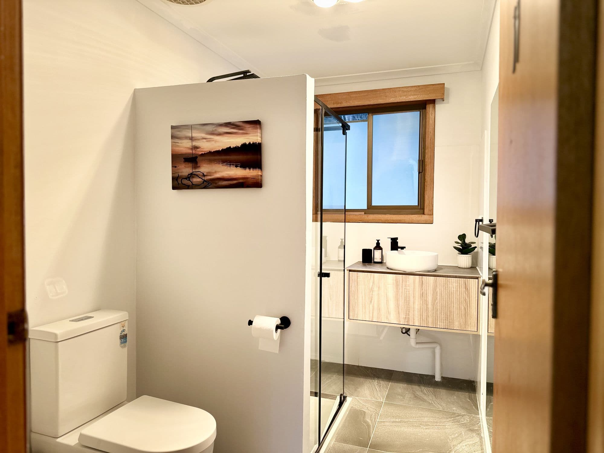 LunaStay — bathroom with walk-in shower, timber vanity and stone-look tiles