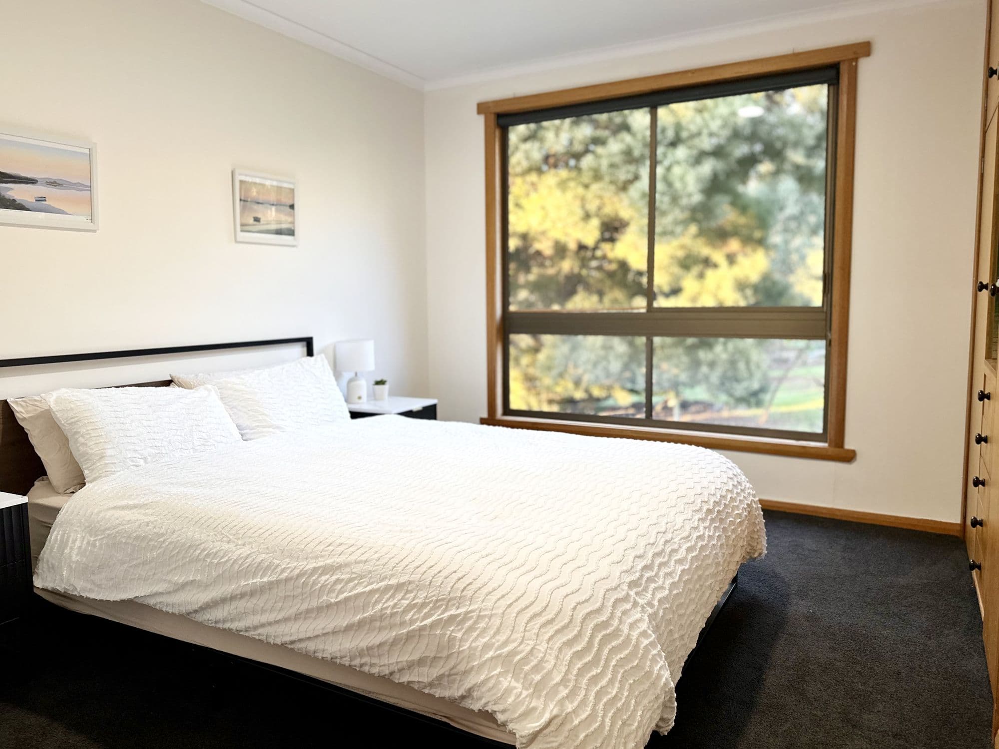 LunaStay — second bedroom with garden outlook and crisp white linen