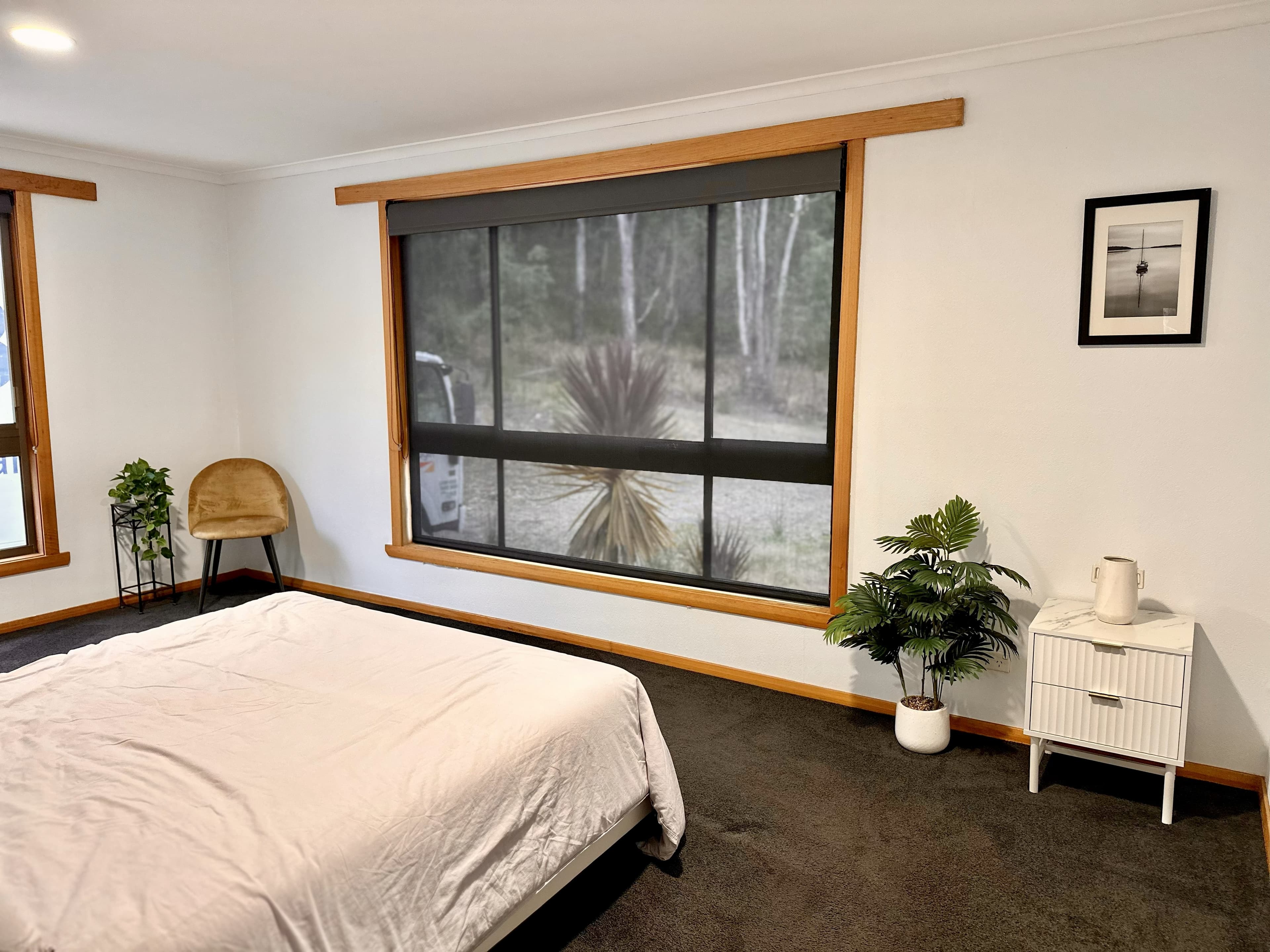 LunaStay master bedroom — king bed, timber-framed windows, bushland view