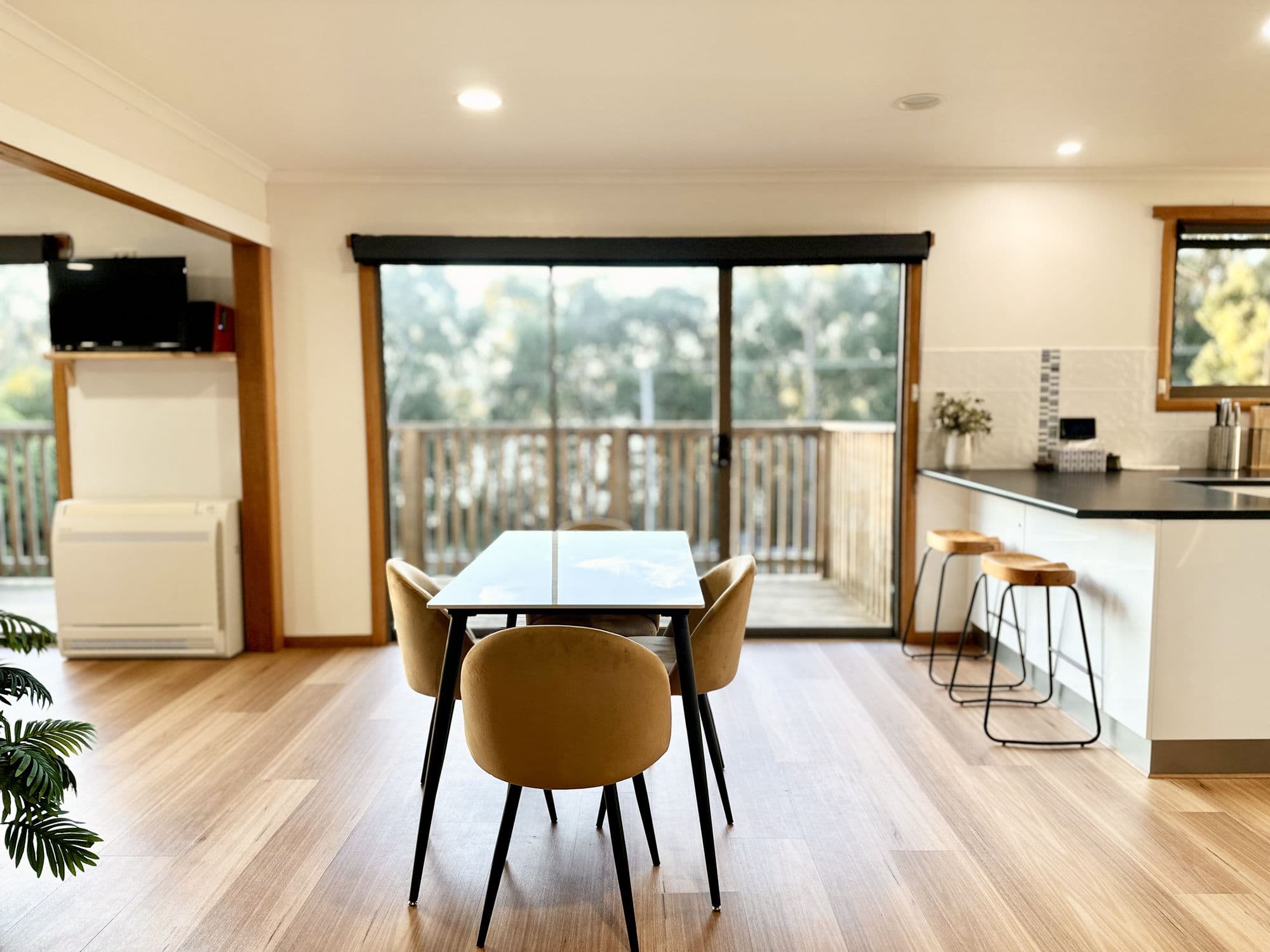 LunaStay — marble dining table beside floor-to-ceiling glass opening to the deck
