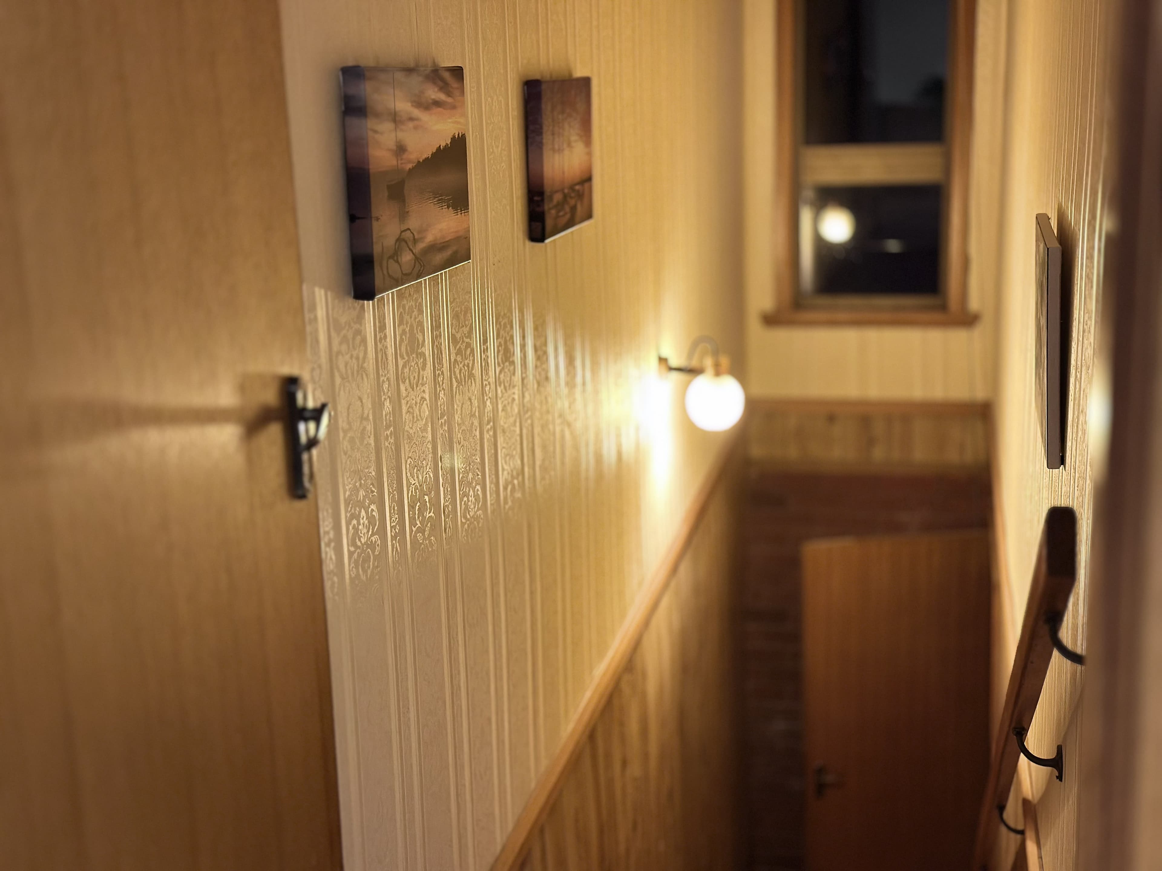 LunaStay — warmly lit hallway with artwork at dusk