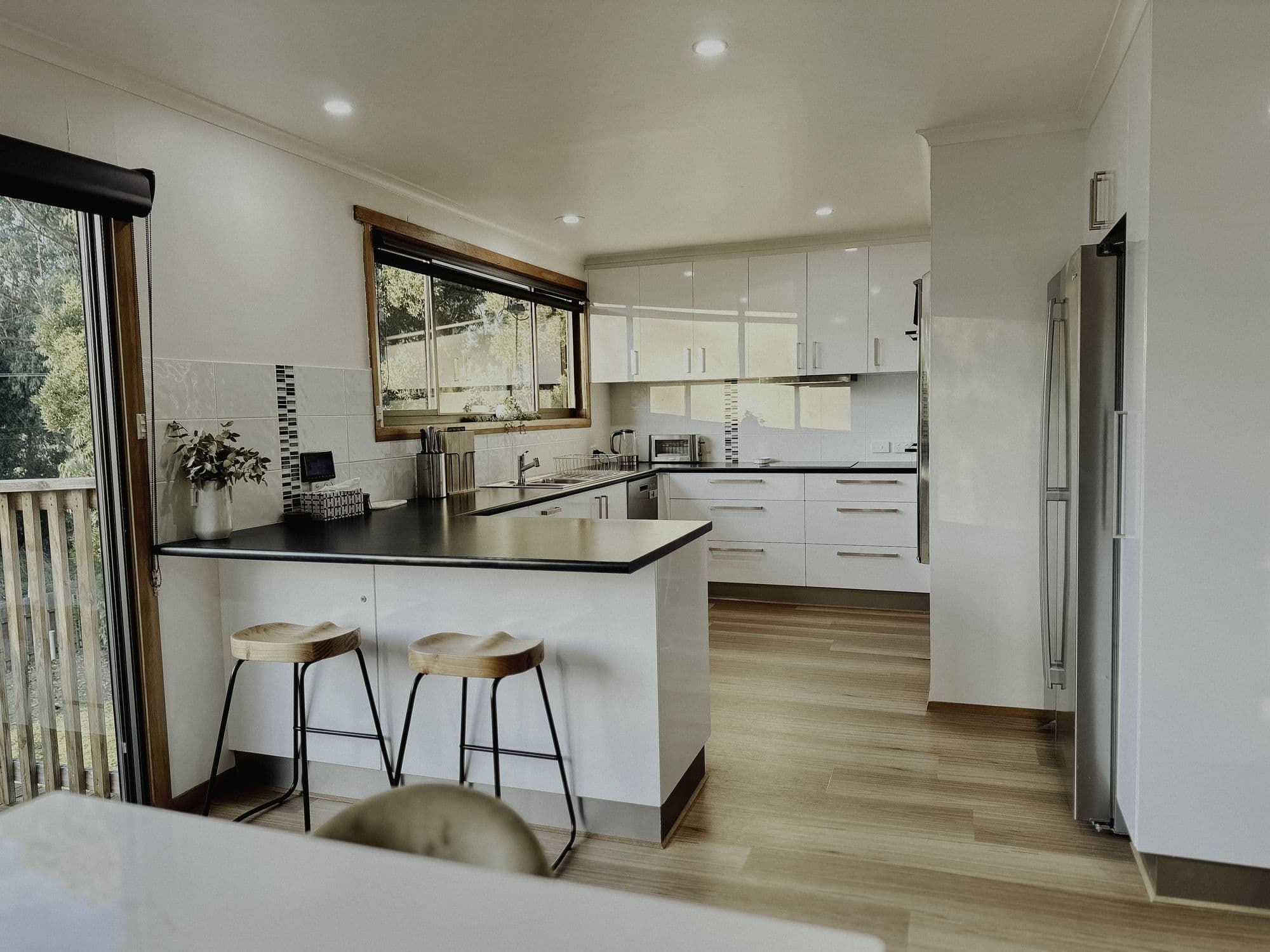 LunaStay — modern white kitchen with breakfast bar and timber stools