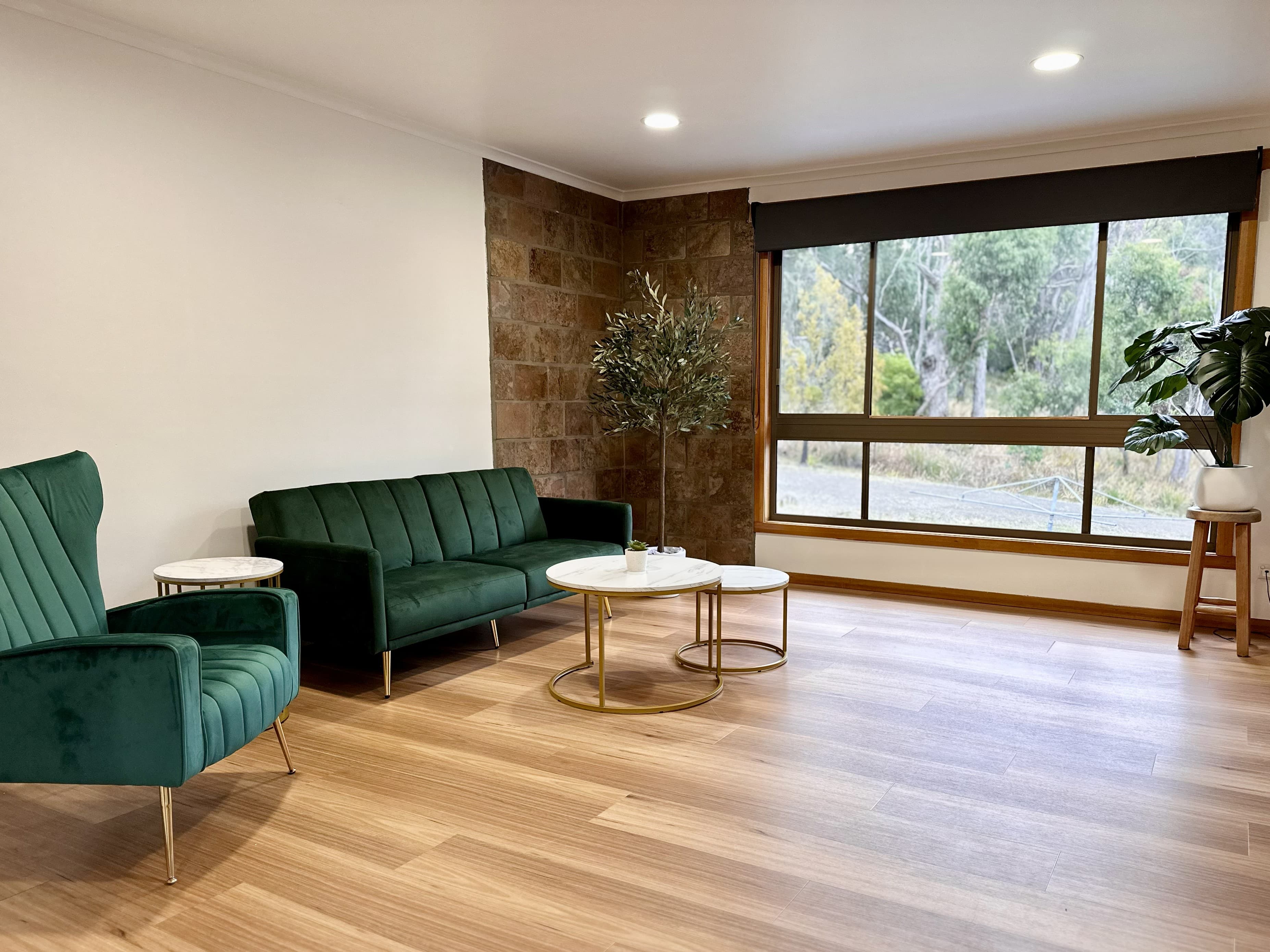 LunaStay living room — green velvet sofa, sandstone feature wall, hardwood floors