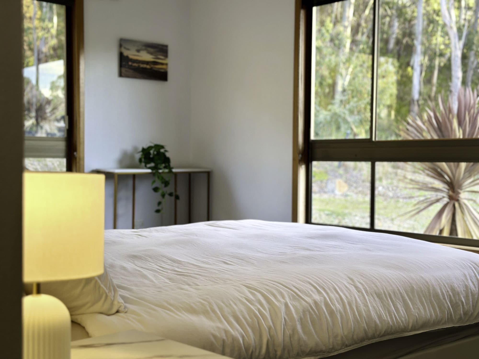 LunaStay master bedroom — corner picture windows framing the native garden