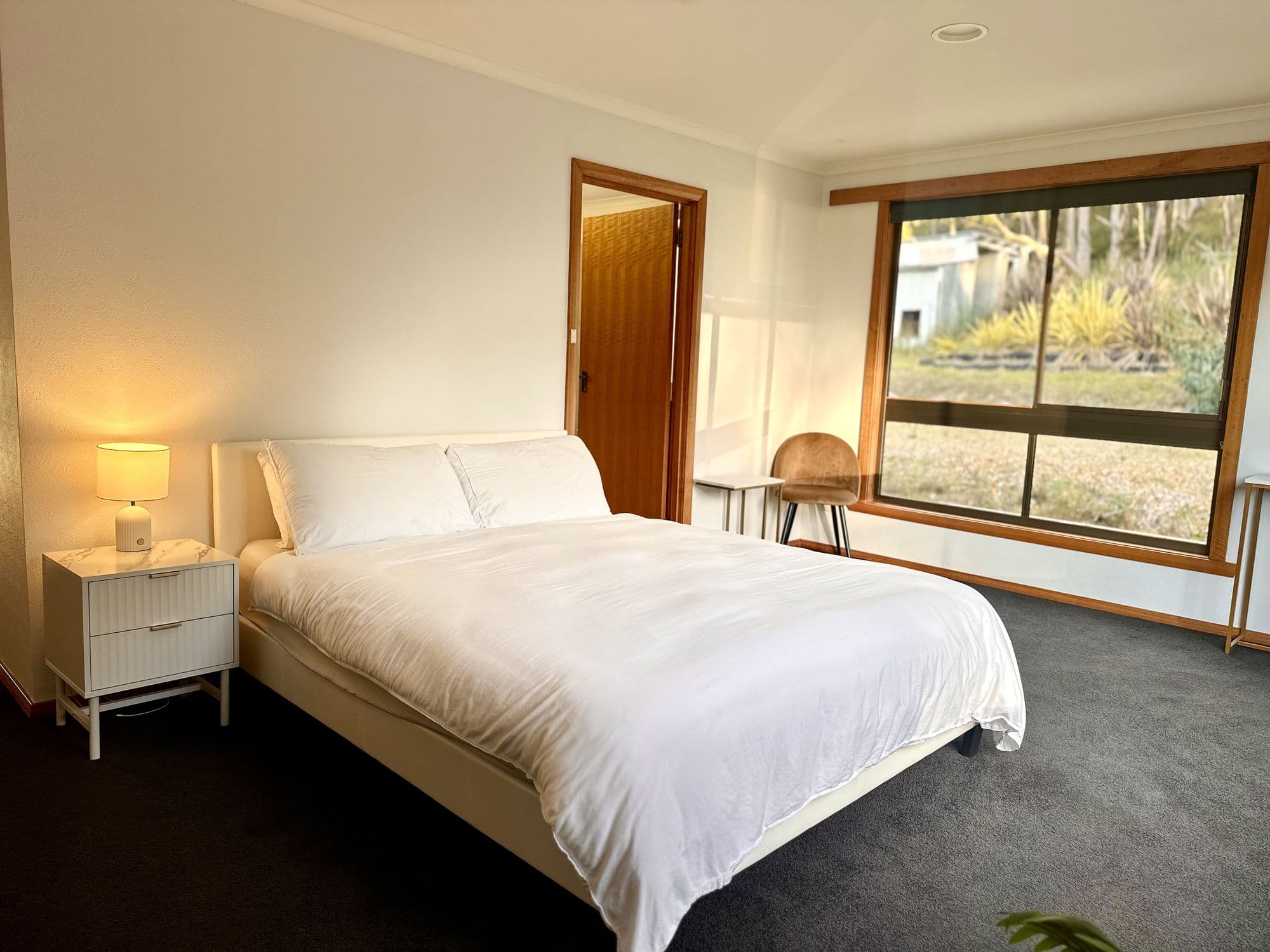 LunaStay — master bedroom with picture windows to the surrounding bushland