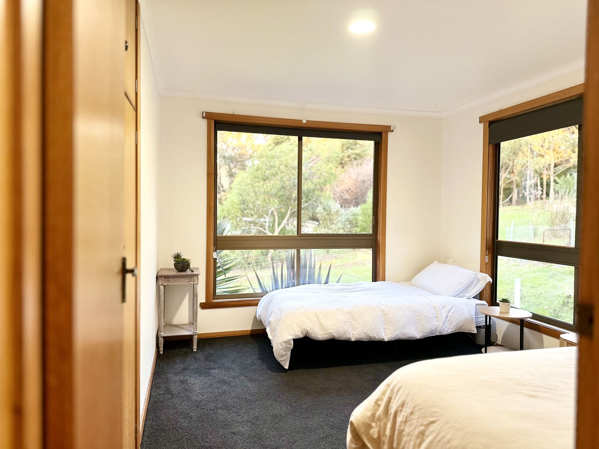 LunaStay — third bedroom with corner windows looking into native gardens
